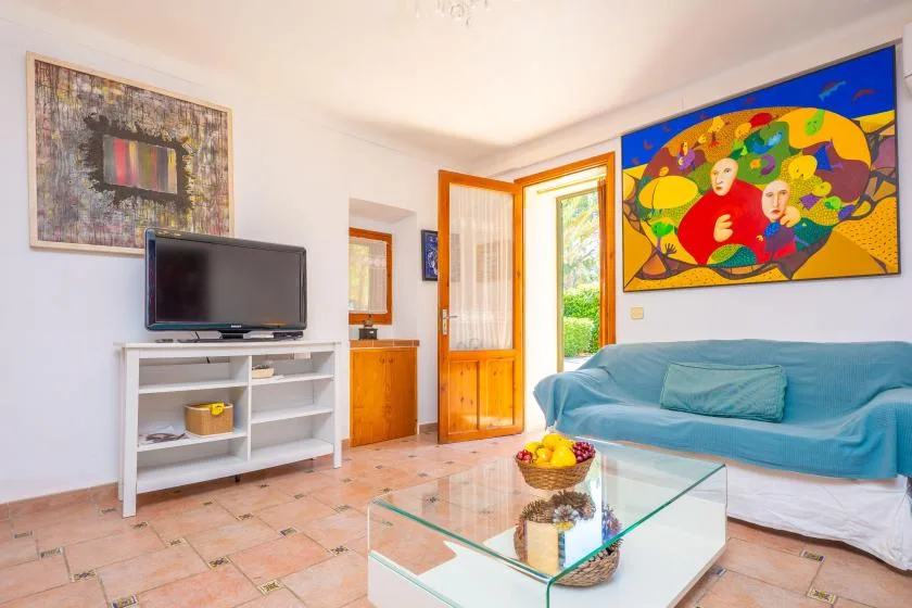 A bright living room with a blue-covered seating area and colorful wall art.