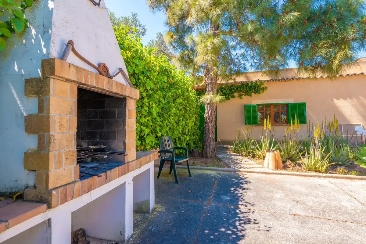 An outdoor patio with a brick barbecue and nearby seating.