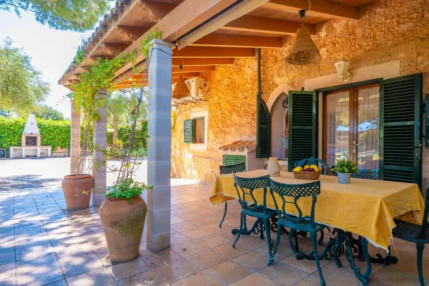 Un comedor en un patio de piedra con una mesa bajo una pérgola de madera.