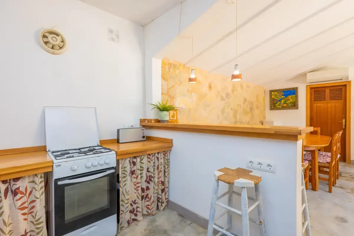 A kitchen with a stove, counter, and a small breakfast bar.