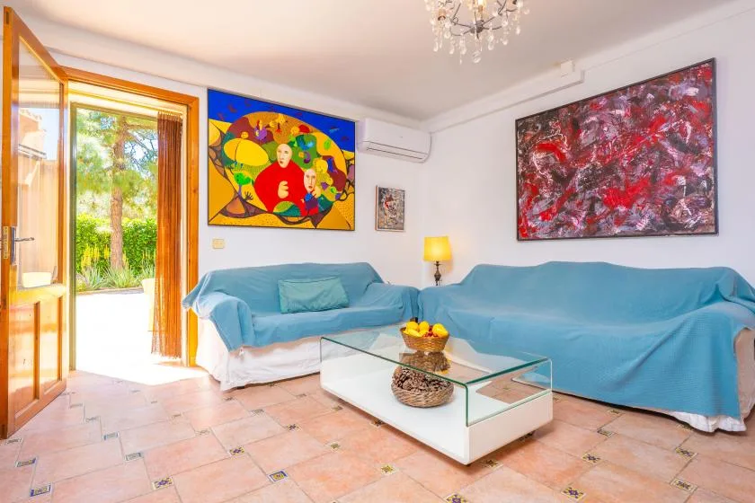 Una sala luminosa con asientos cubiertos de azul, obras de arte coloridas y una mesa de centro de vidrio.