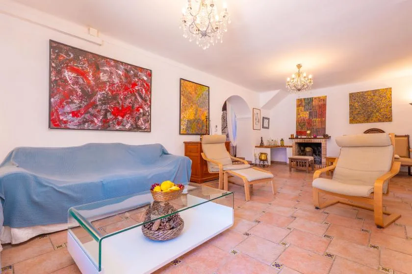 A living room with seating, colorful wall art, and a glass coffee table.