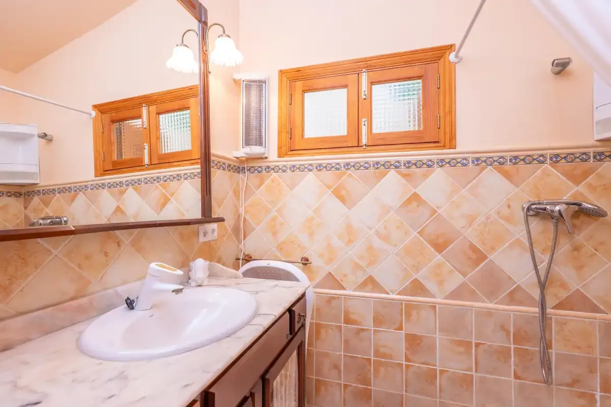 A tiled bathroom with a sink, mirror, and shower.
