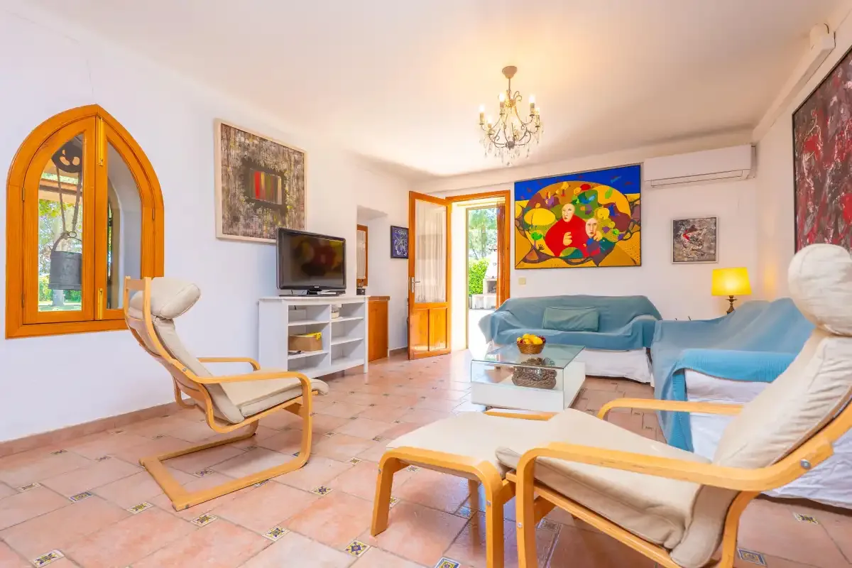 A bright living room with seating, a television, and colorful wall art.