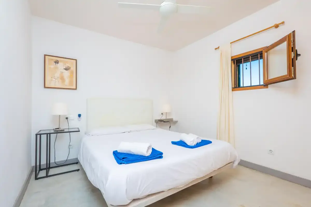 A bright bedroom with a double bed and an open window.