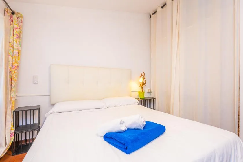 A bedroom with a neatly made bed and a folded blue towel.
