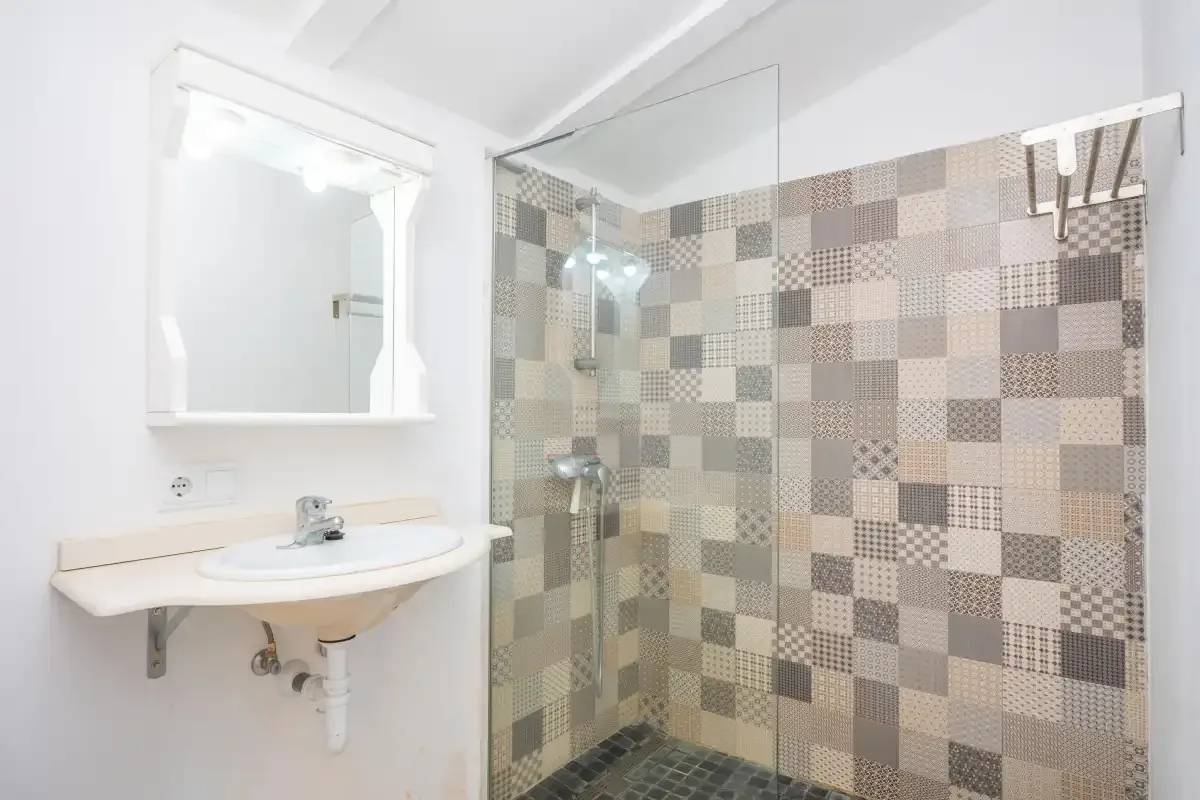 A bright bathroom with a wall-mounted sink and tiled shower.