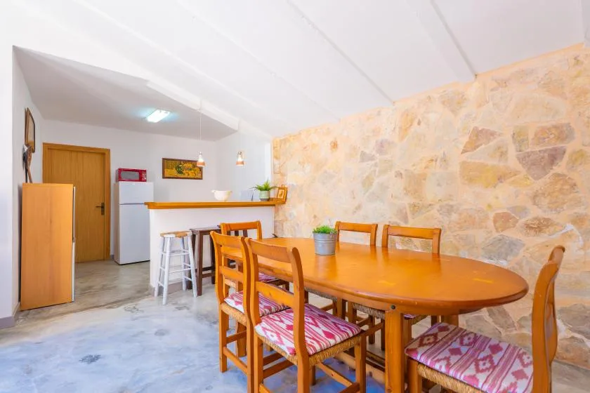 A dining area with a wooden table and chairs beside a stone wall.