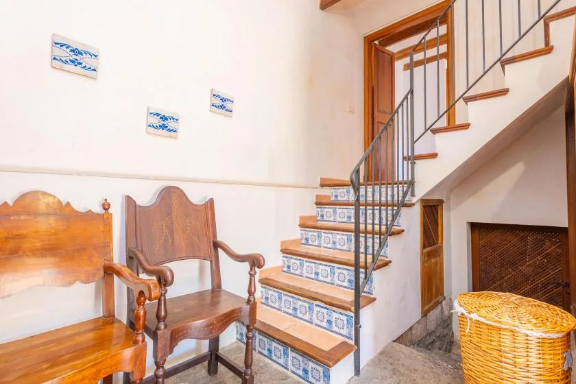 A bright interior shows wooden seating beside a staircase with patterned tile risers.