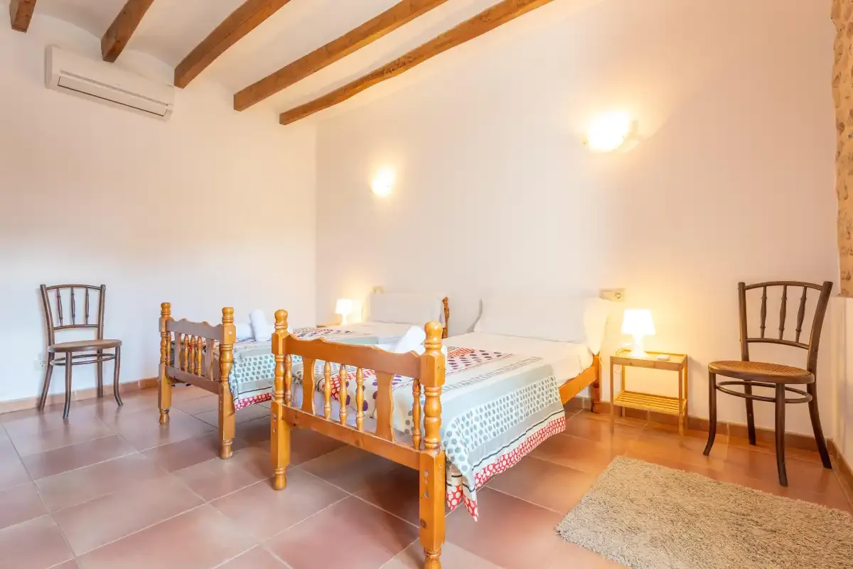 A bright bedroom with two wooden beds and exposed ceiling beams.