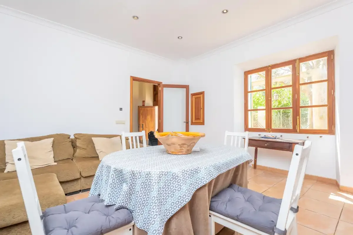 A dining area with a table set beside a large wooden-framed window.