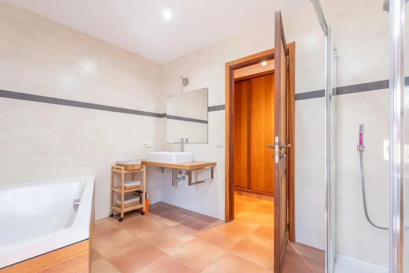 A bright bathroom with a sink, bathtub, and glass shower enclosure.