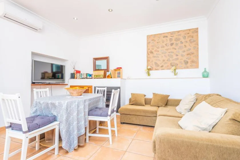 A bright living and dining area with a table, seating, and a wall-mounted television.