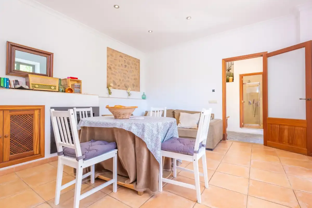 A dining area has a table with a patterned cloth and white seating.
