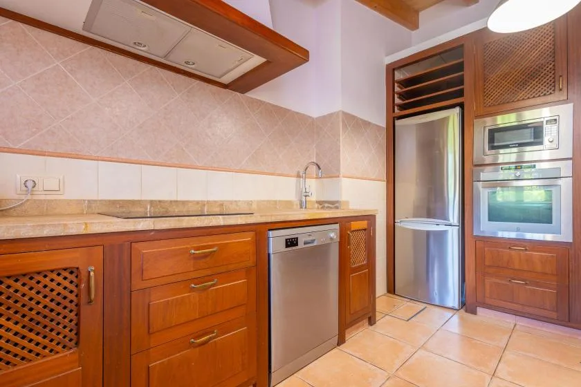 A kitchen with wooden cabinets, a countertop, and built-in appliances.