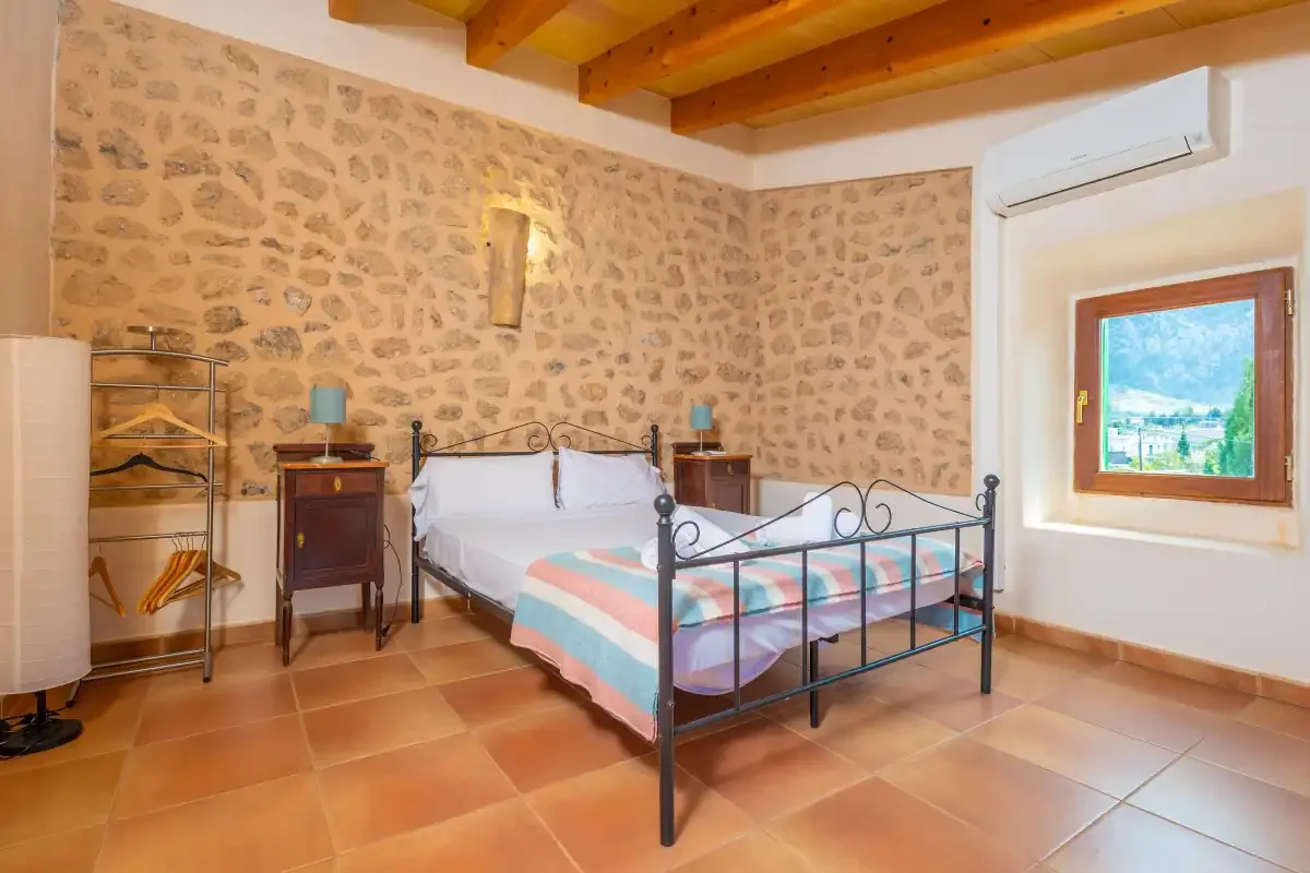 A bedroom with a metal bed, patterned bedding, and exposed wooden ceiling beams.