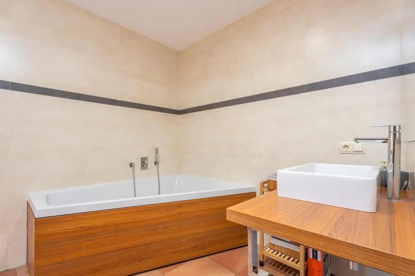 A bathroom with a bathtub and a wooden vanity.