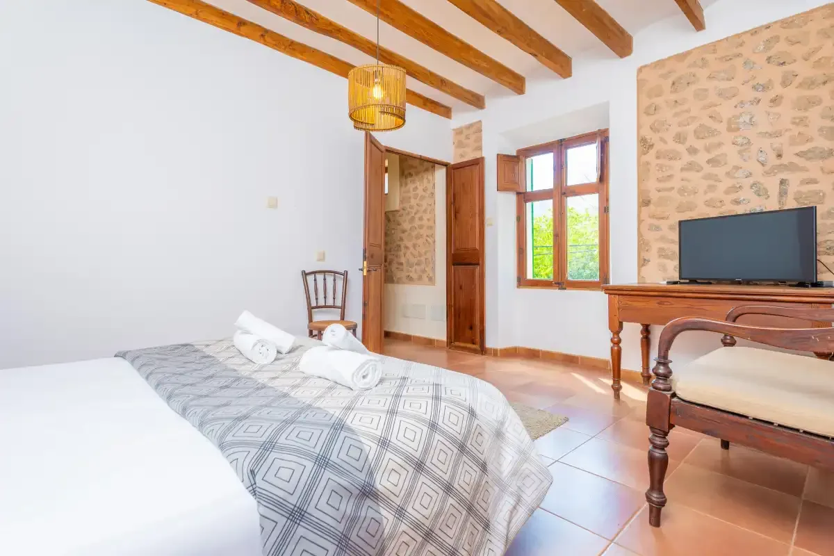 A bedroom with patterned bedding, exposed wooden beams, and a television.