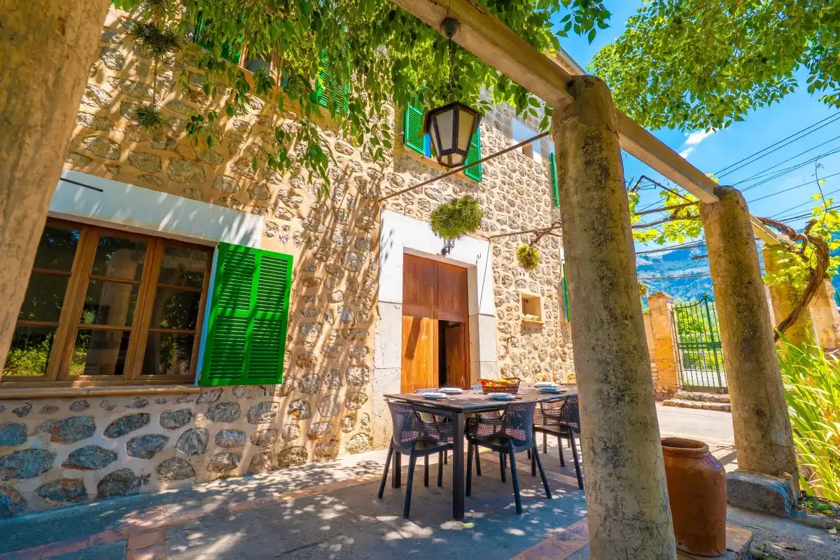 A stone courtyard with outdoor seating beneath leafy trees.