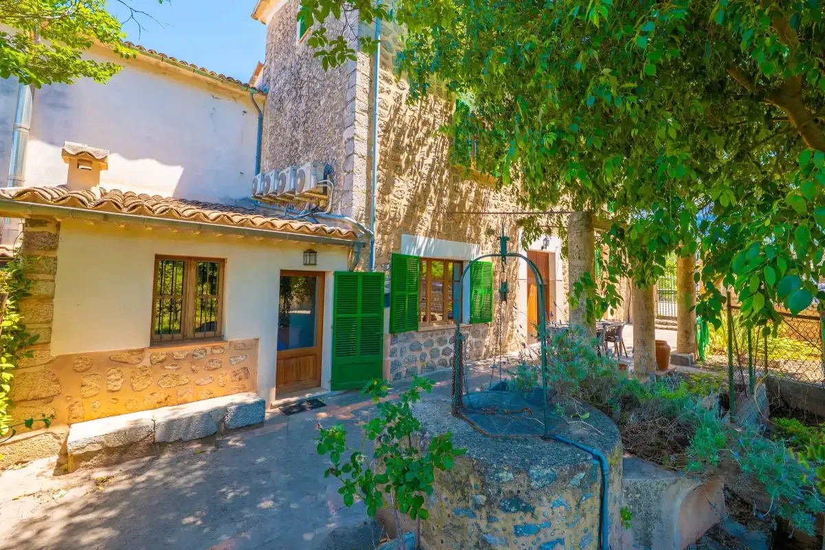 A stone-and-plaster house beside a leafy garden courtyard.