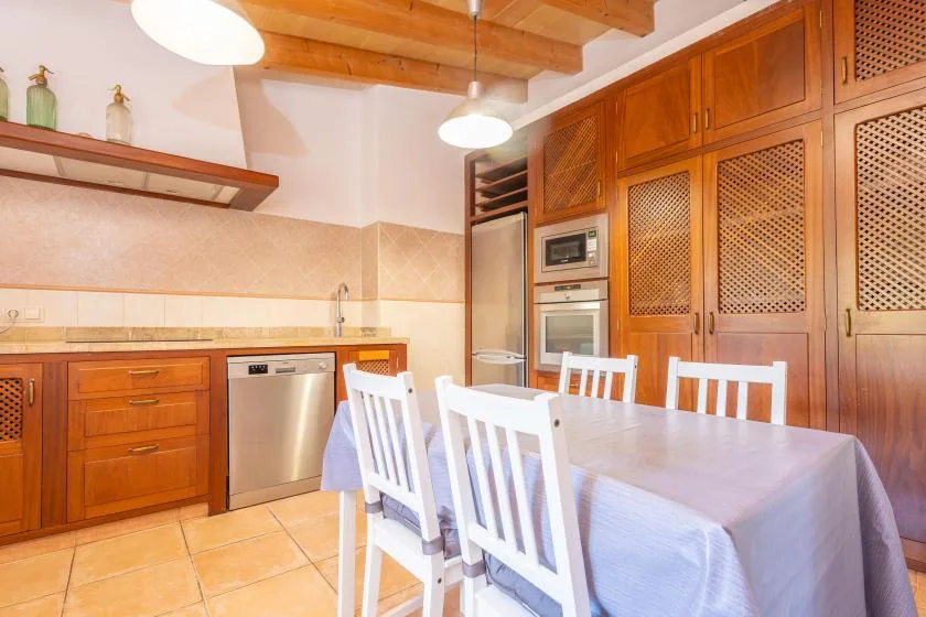 A kitchen and dining area with wooden cabinets and a table surrounded by chairs.