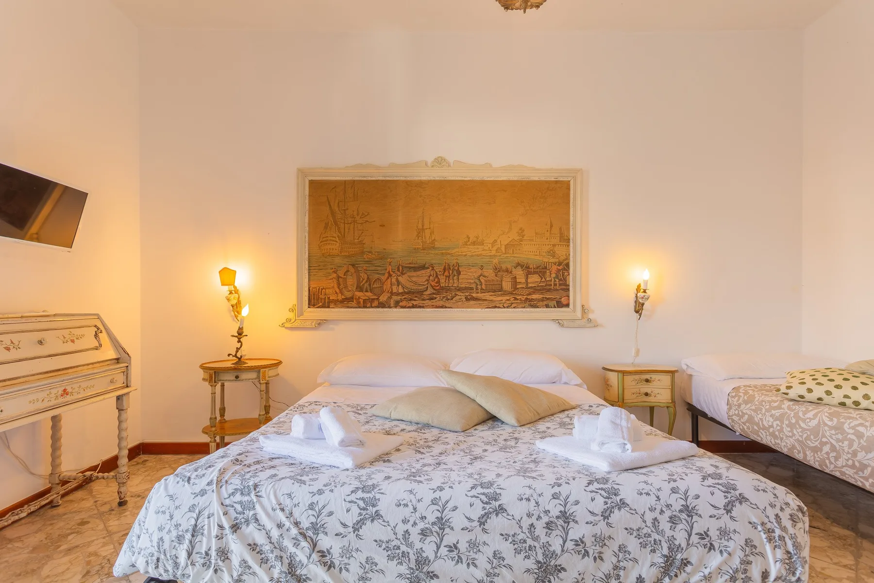 Un dormitorio con una cama grande, mesitas de noche y una obra enmarcada en la pared.
