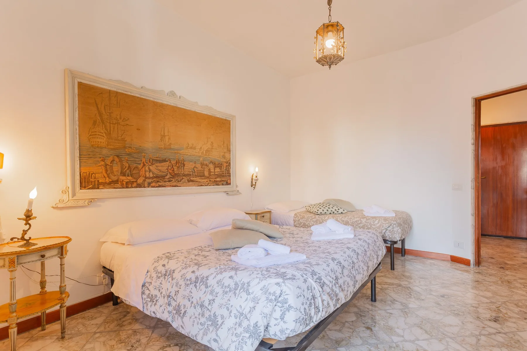 A bedroom with two beds, patterned bedding, and a large framed wall artwork.