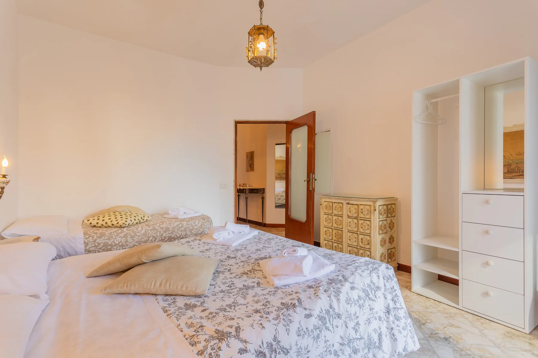 A bedroom with patterned bedding and an open door leading to another room.