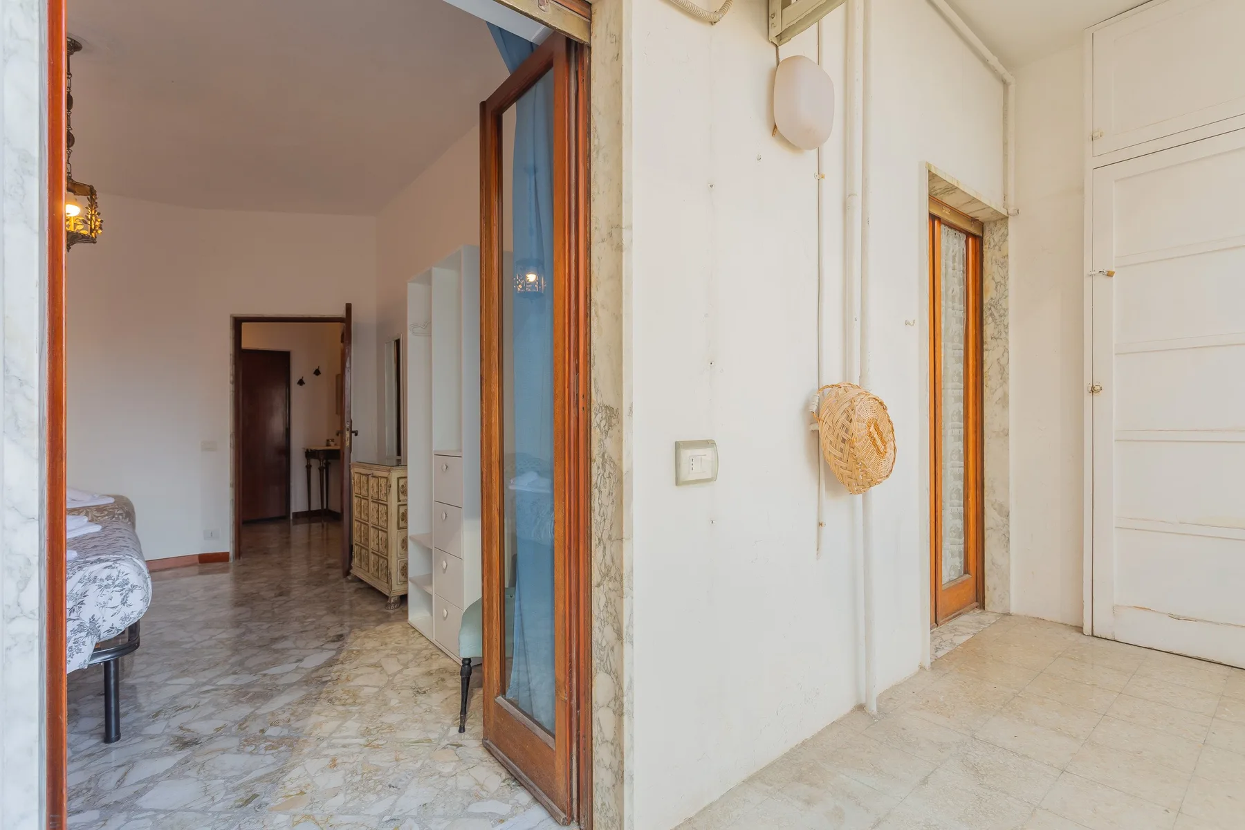 An interior hallway with open doorways and a view into a bedroom.