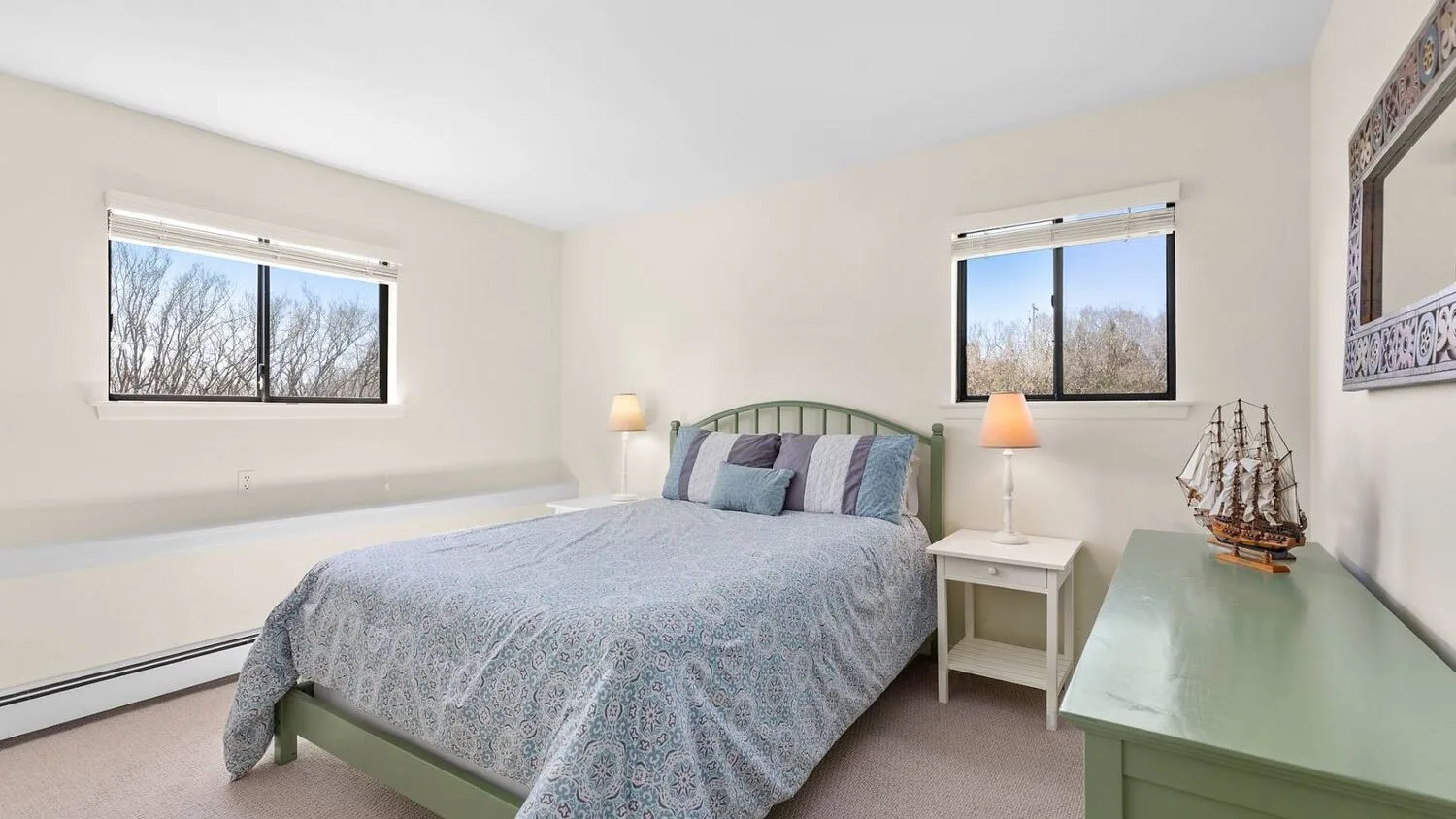 A bedroom with a bed, bedside table, and windows.