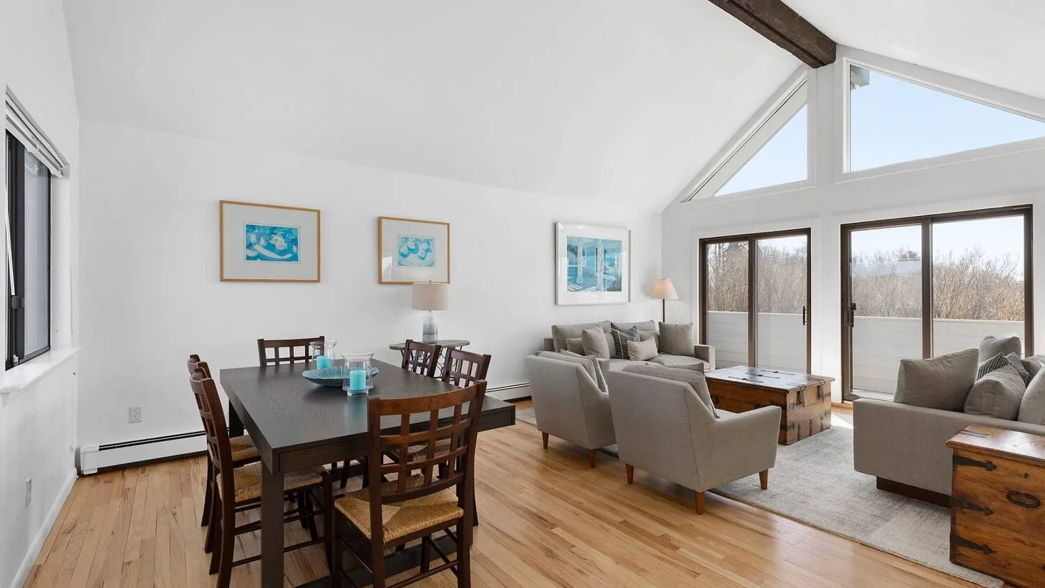 A bright open-plan dining and living area with large windows and seating.