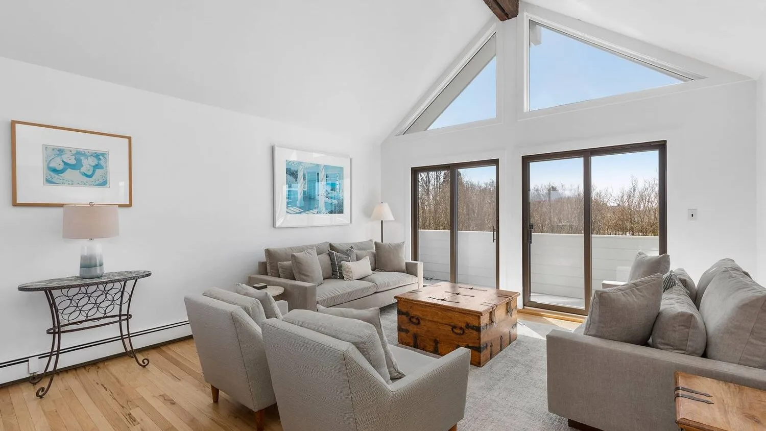 A bright living room with seating around a wooden coffee table and large windows.
