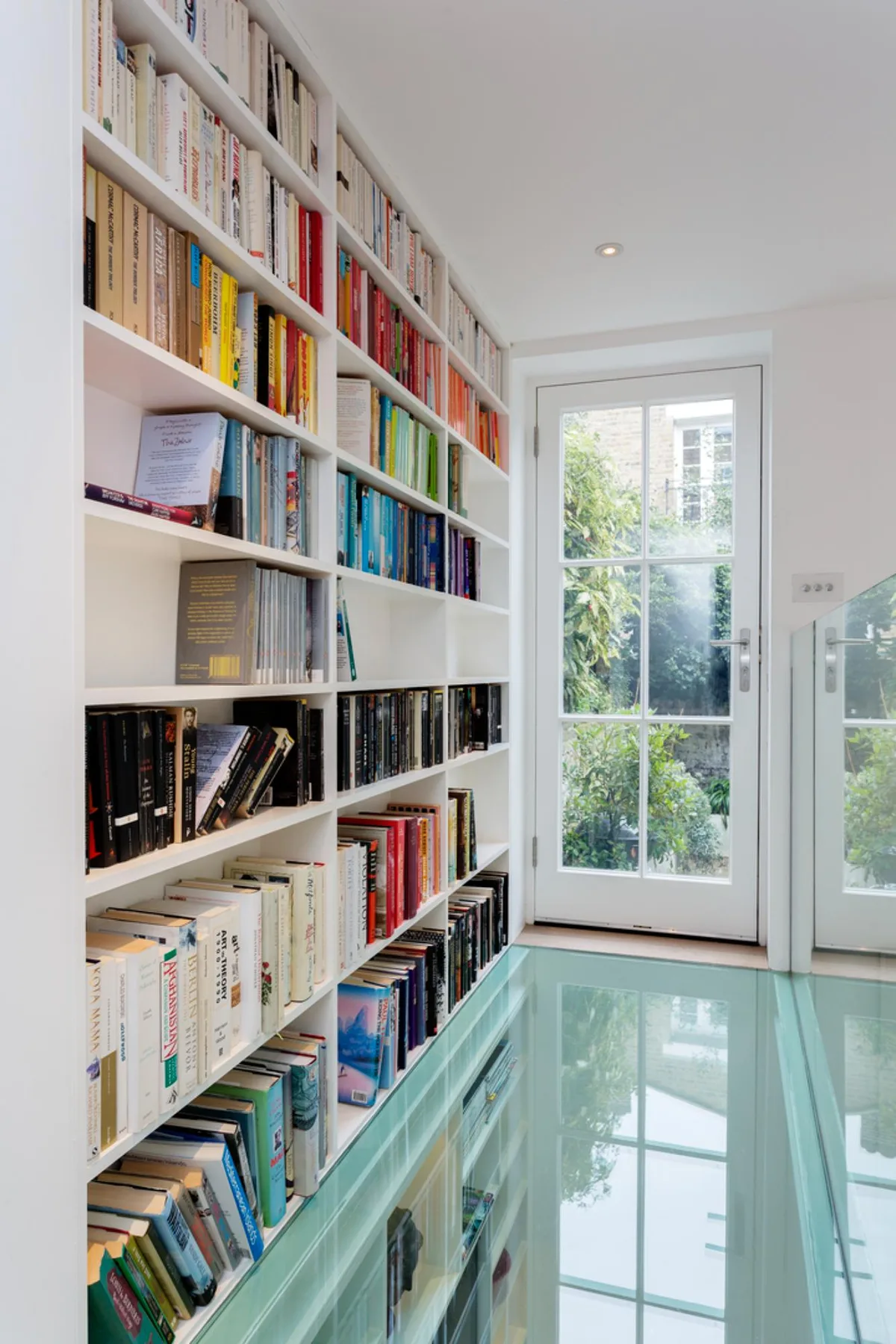 Una habitación luminosa con estanterías de libros junto a una puerta de vidrio.