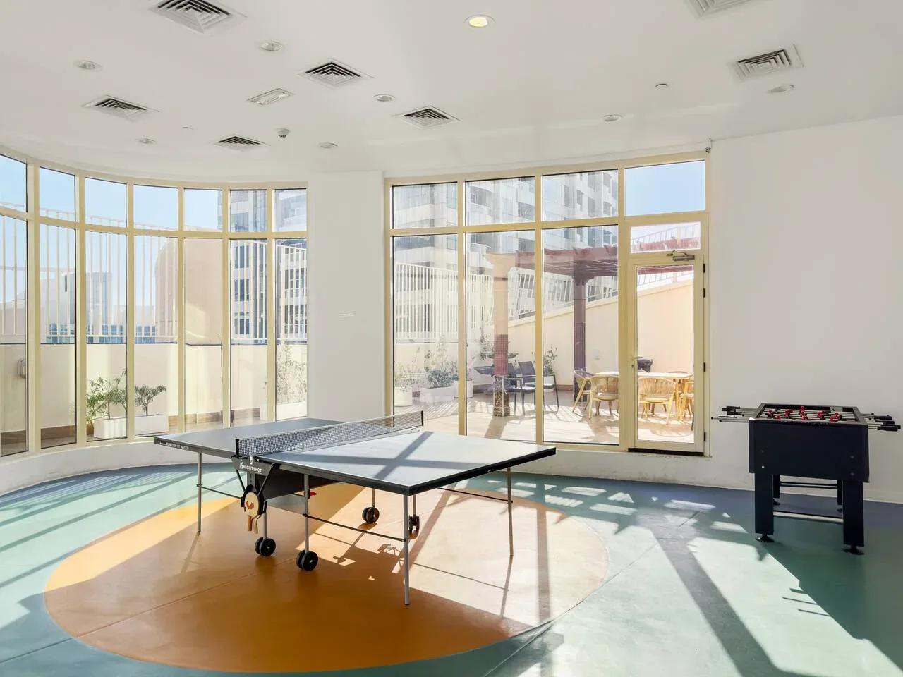 Una luminosa sala de recreación con una mesa de ping-pong y una mesa de futbolín.