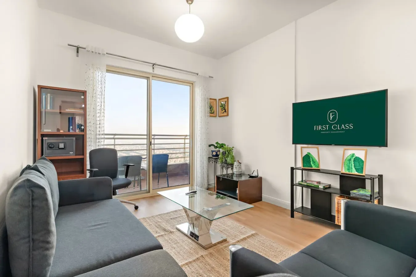 Una sala de estar luminosa con asientos, una mesa de centro de vidrio y puertas corredizas al balcón.