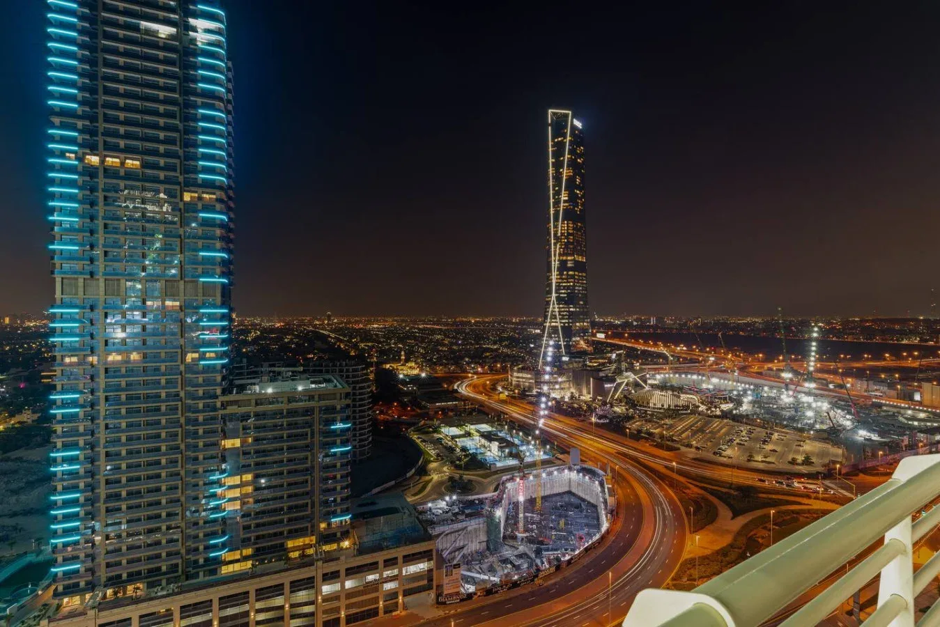 Paisaje urbano nocturno con edificios iluminados y vías curvas.