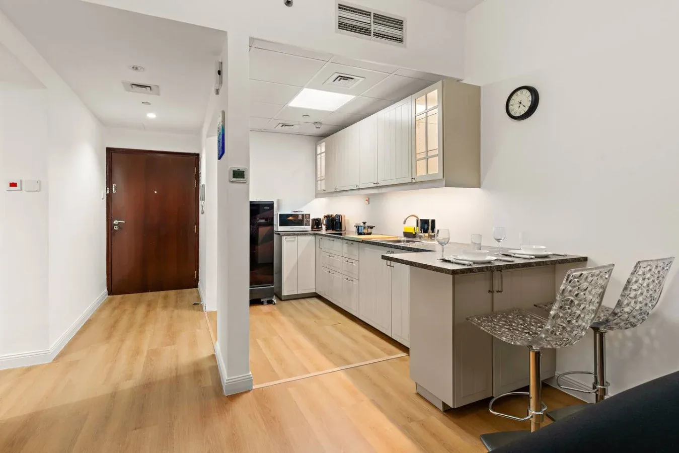 Una cocina luminosa con gabinetes blancos, una encimera y asientos de barra.