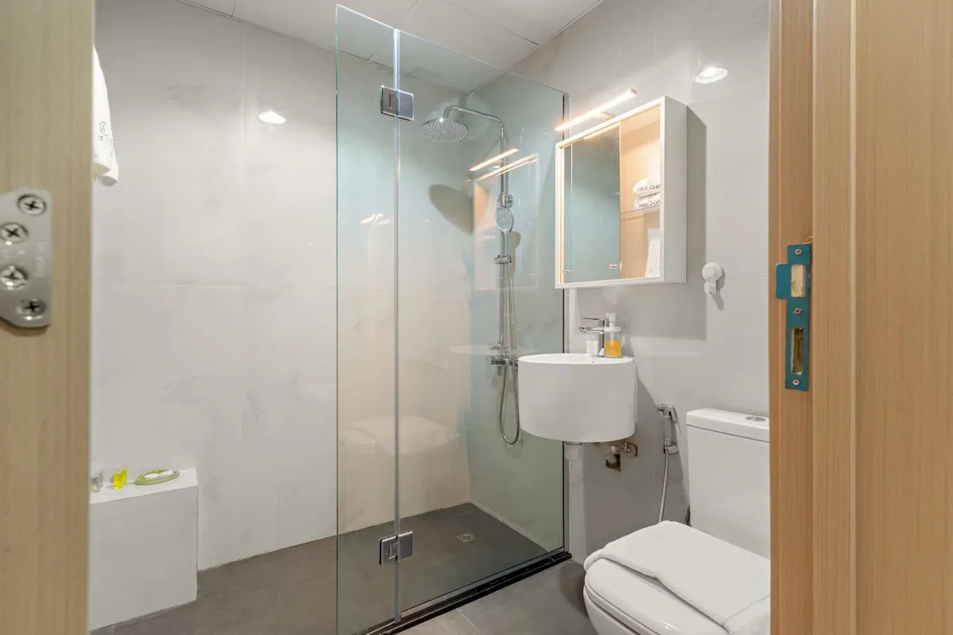 Un baño luminoso con ducha de cristal, lavabo e inodoro.