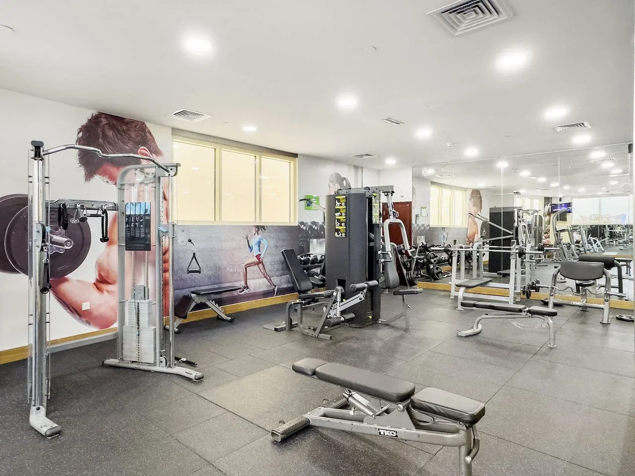 Un gimnasio con máquinas de pesas, bancos y equipo de ejercicio.