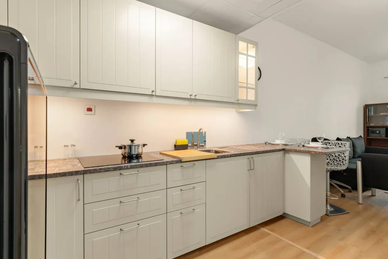 Una cocina luminosa con gabinetes blancos, encimeras y un comedor.