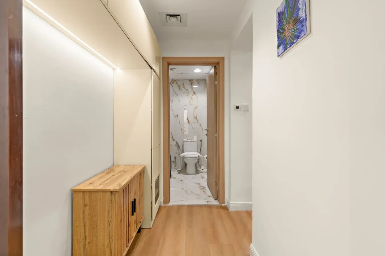 Un pasillo con un mueble de madera y una puerta abierta a un baño.