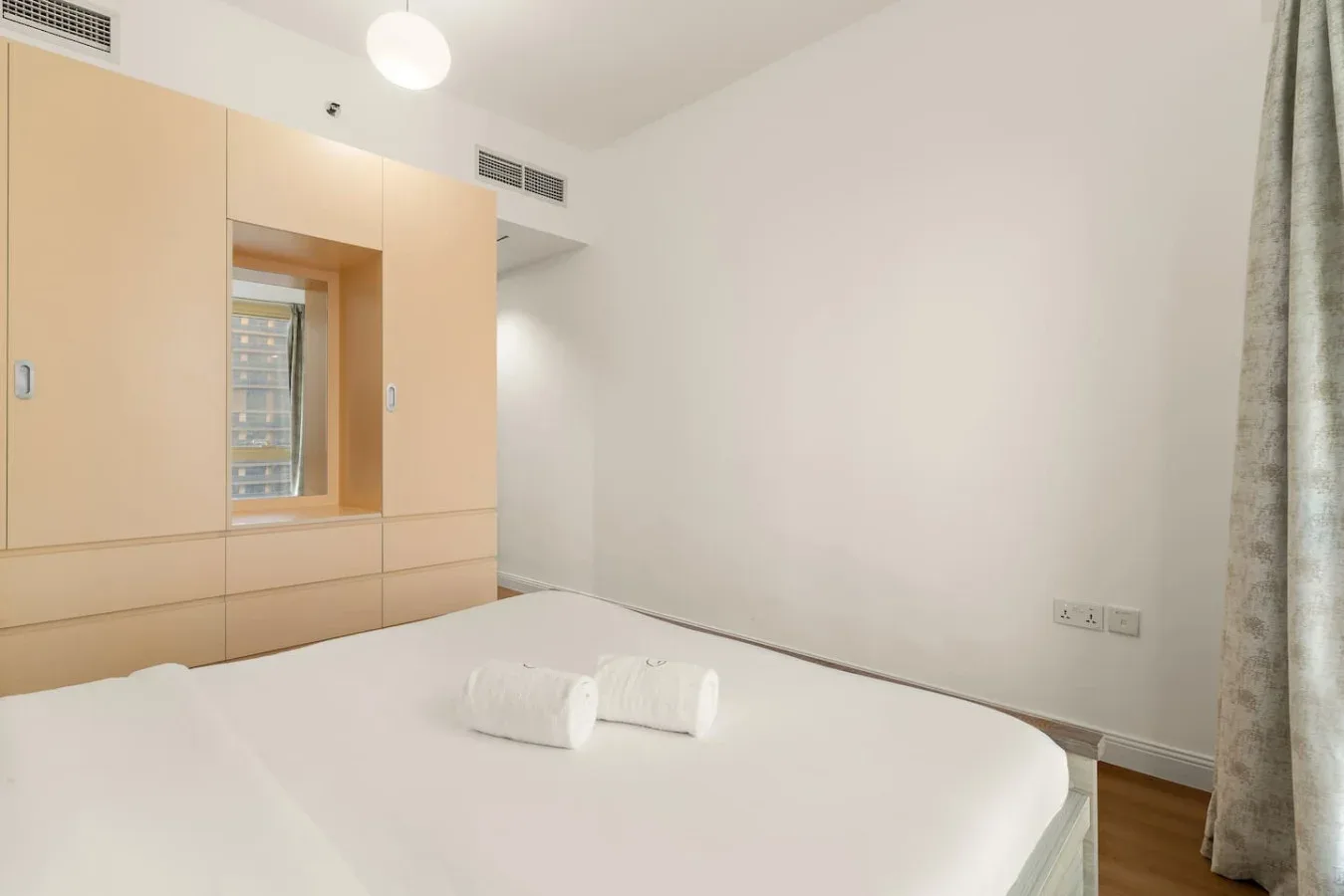 Un dormitorio con una cama bien tendida y armarios empotrados de madera.