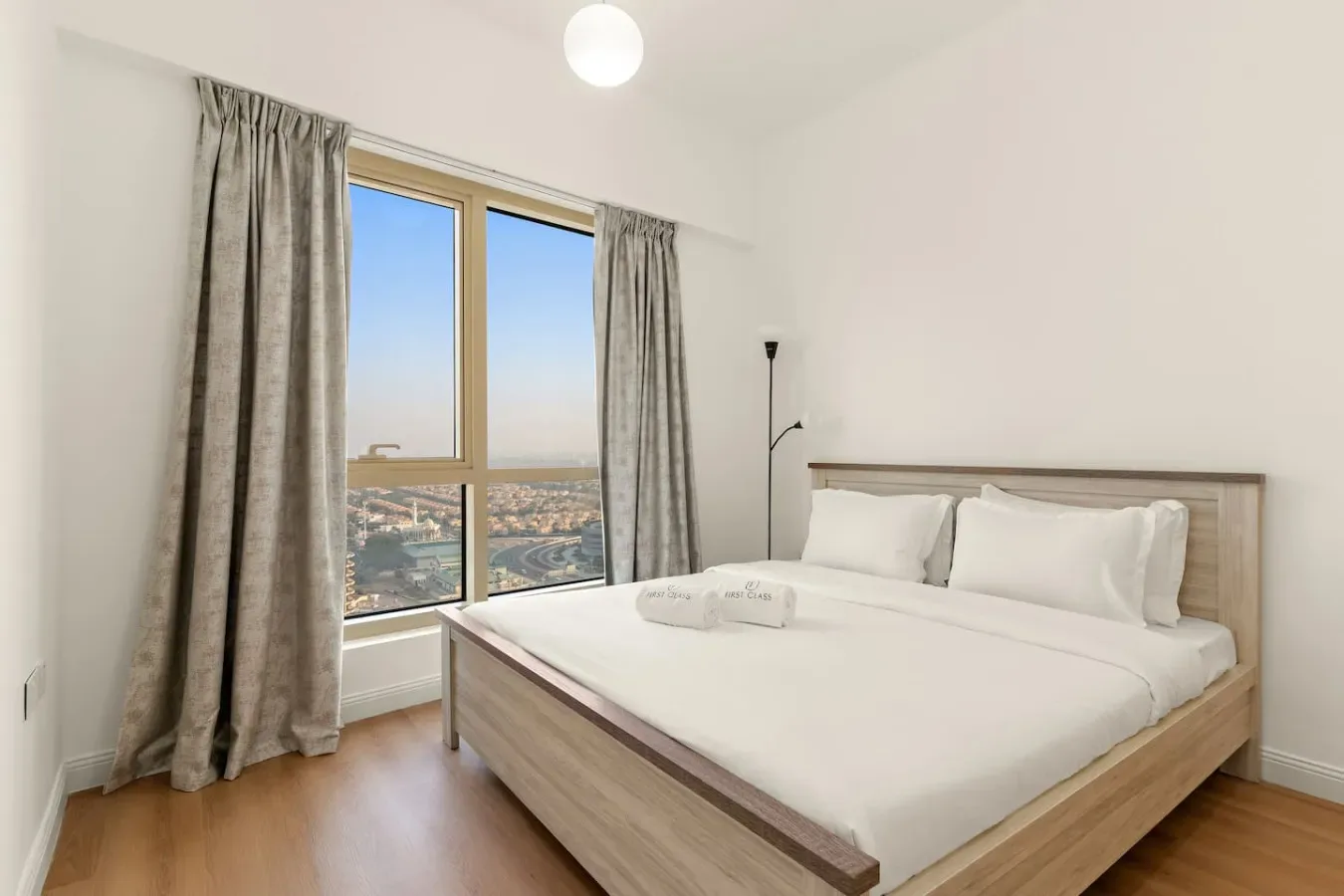 Un dormitorio luminoso con una cama bien hecha junto a una ventana grande.