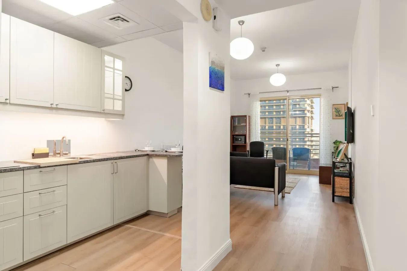 Una cocina luminosa se abre a una sala de estar con asientos y grandes ventanas.