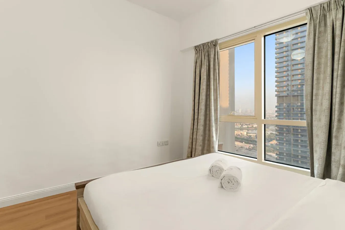 Un dormitorio luminoso con una cama tendida junto a una ventana grande.