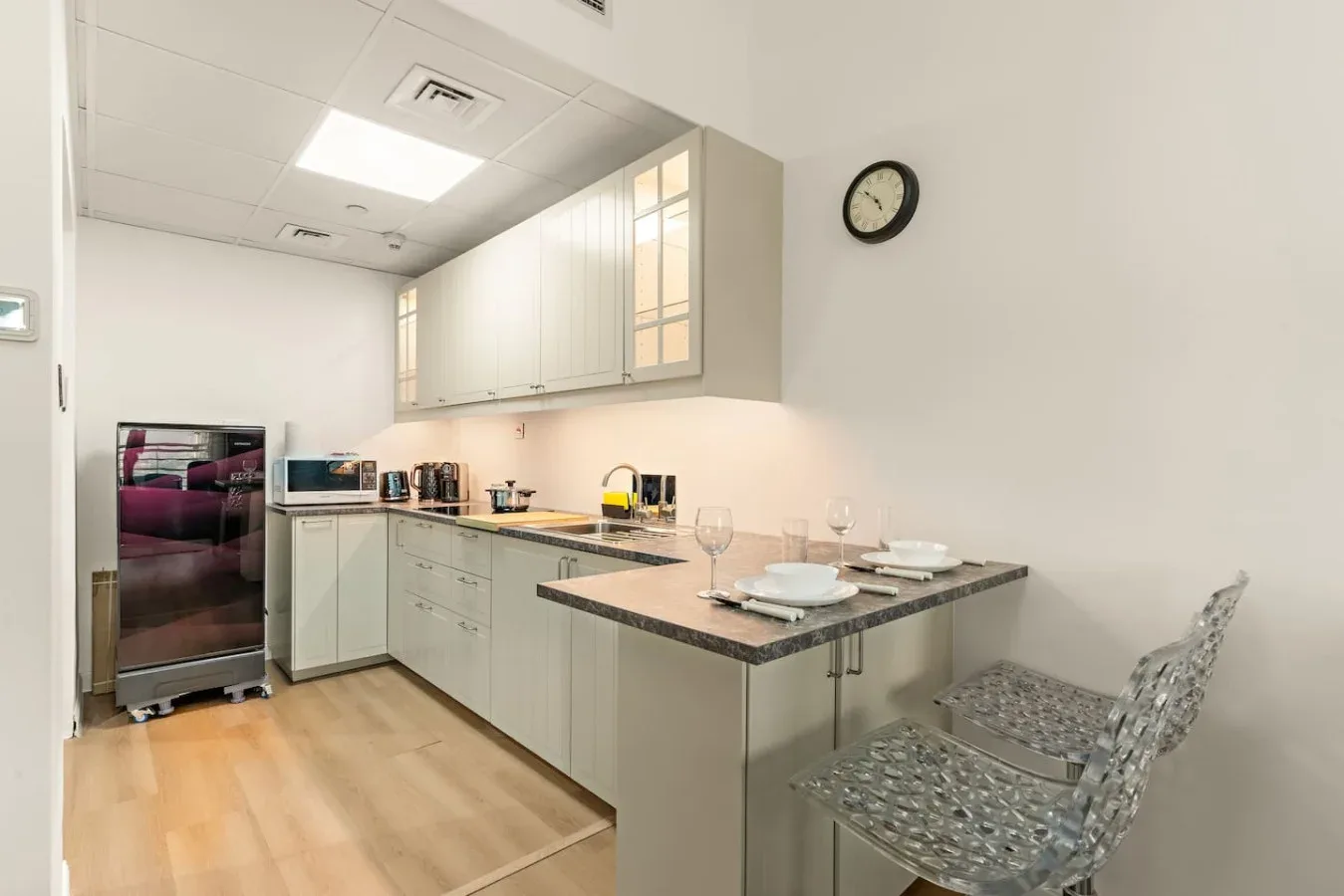 Una cocina luminosa con gabinetes claros, una encimera y asientos.