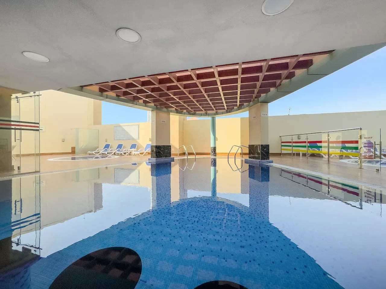 Una piscina cubierta con agua azul y asientos al fondo.