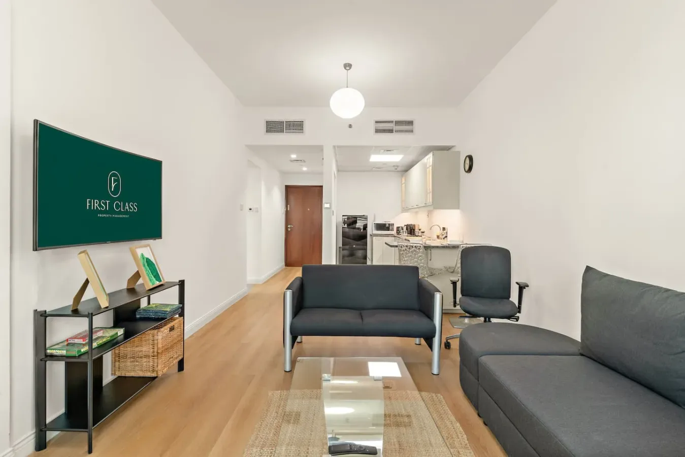 Una sala luminosa con asientos, una mesa de centro de vidrio y una cocina abierta.