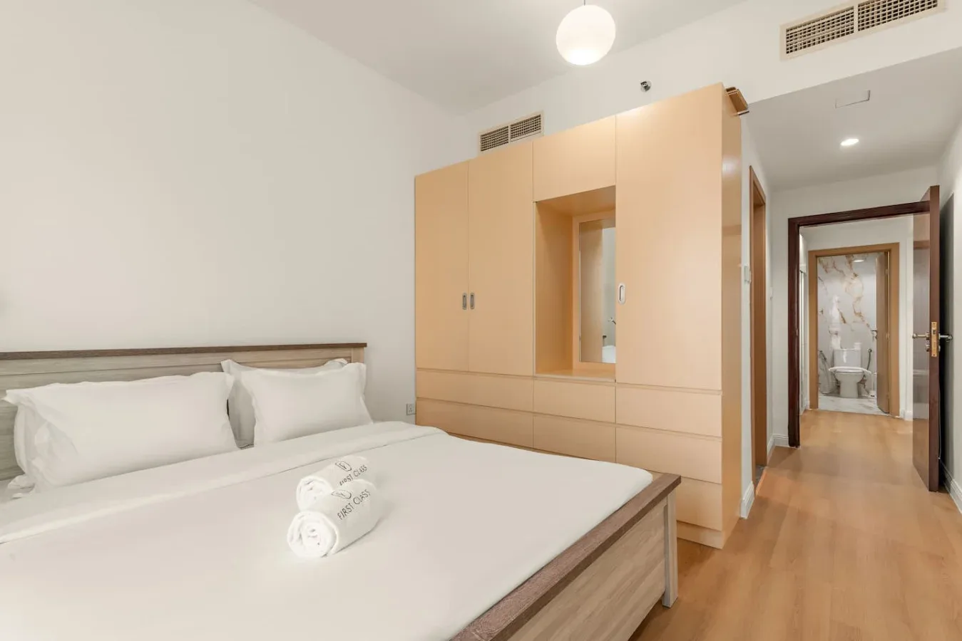 Un dormitorio con una cama bien tendida y muebles de madera clara.