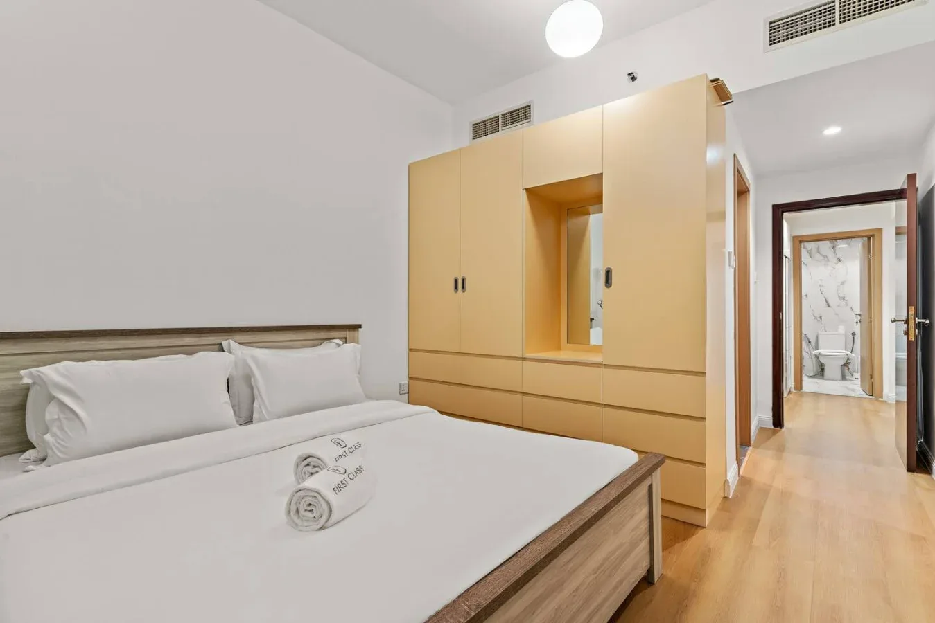 Un dormitorio con una cama, ropa de cama blanca y armarios de madera.